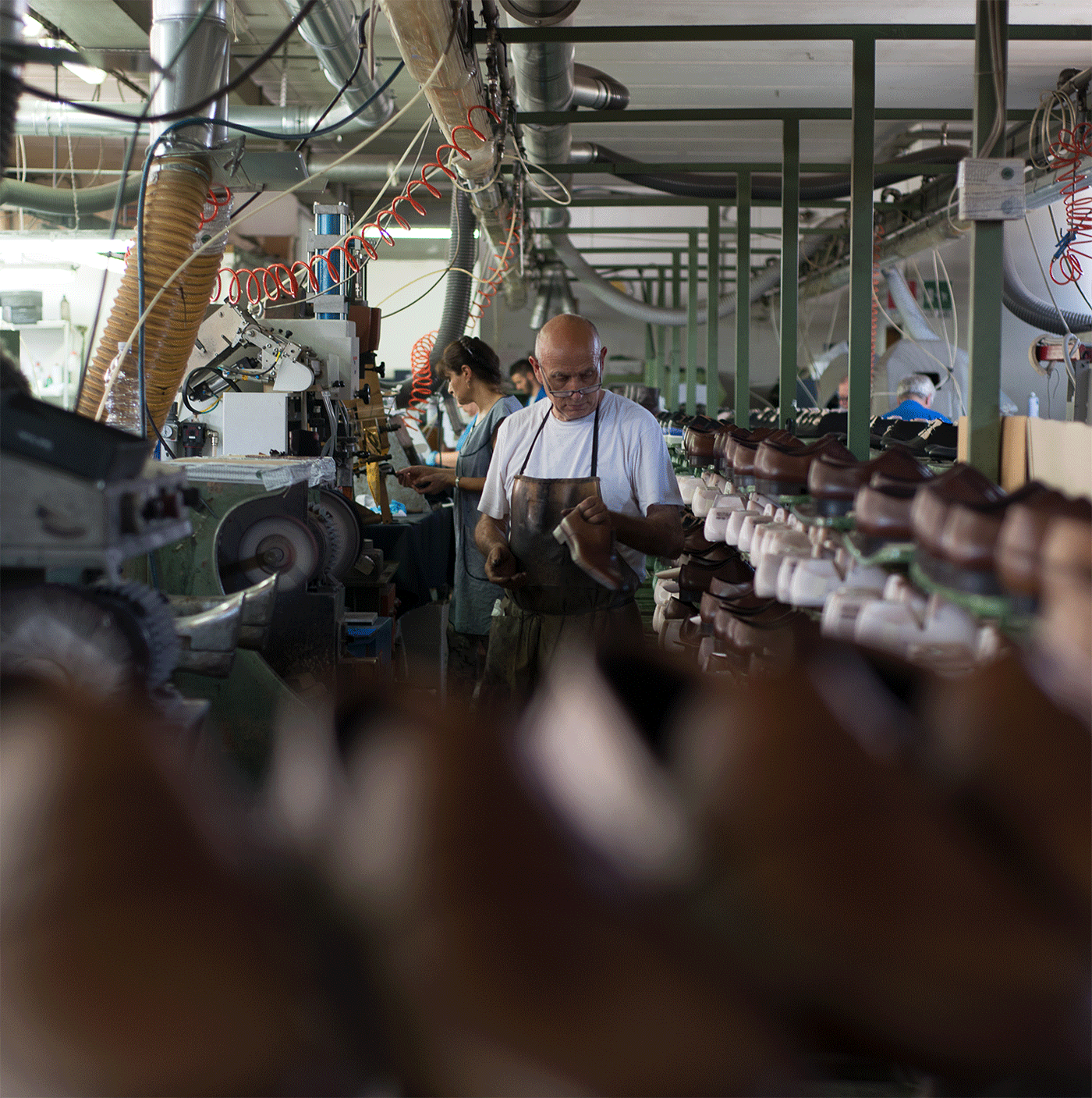 A maker inspecting a shoe on the shoemaking floor